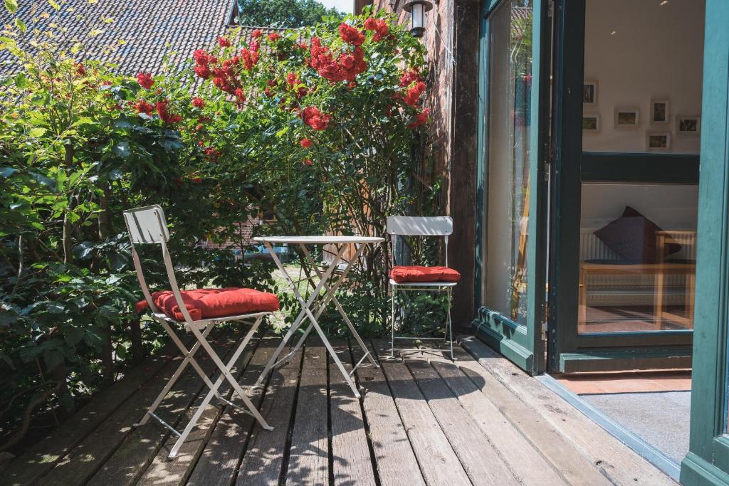 two chairs and a table on a porch with roses at Oesenhof - Dielenwohnung in Bad Fallingbostel