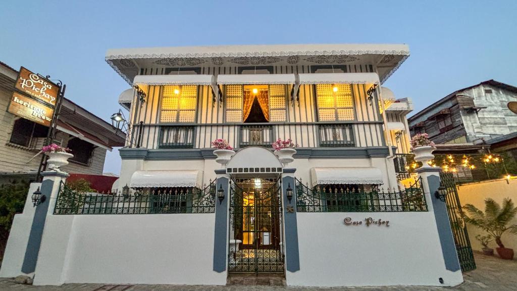 a white building with a gate in front of it at Casa Pichay Family Room in Vigan