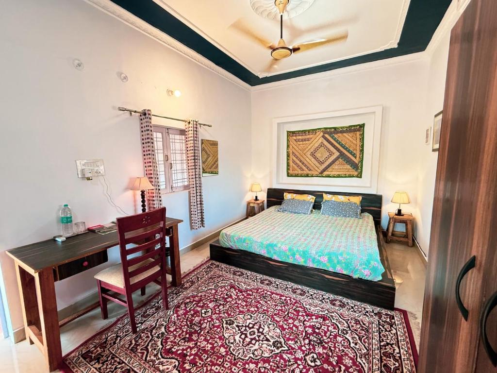 a bedroom with a bed and a desk and a chair at Comfort and Cozy in Orchha