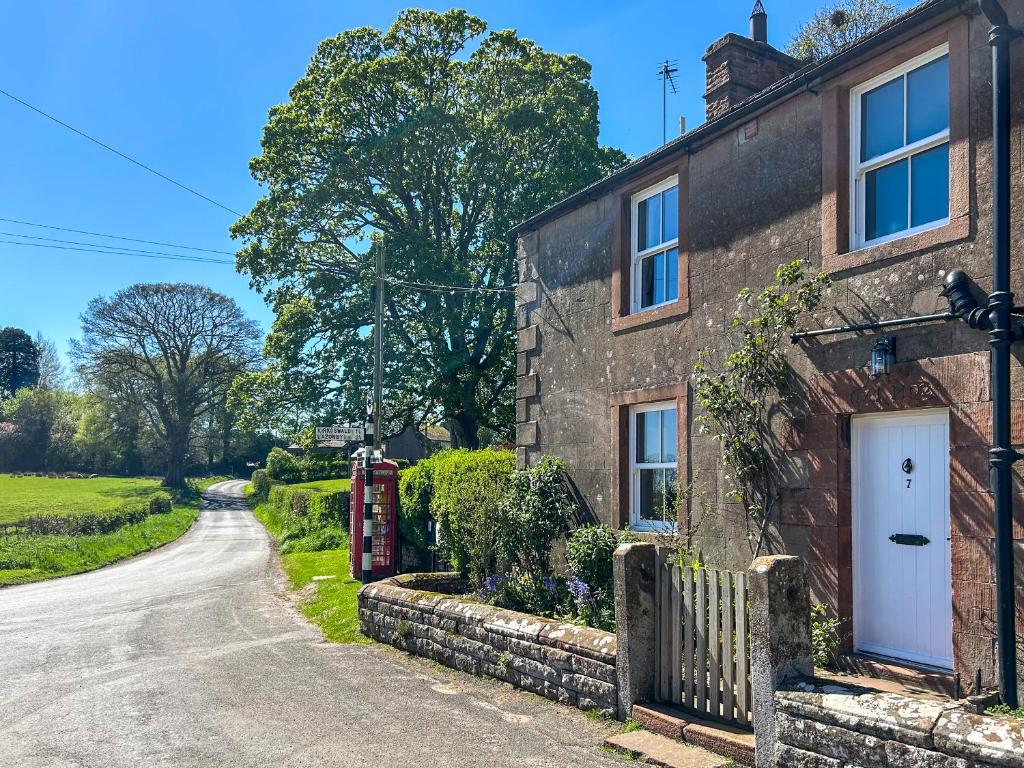 a brick house with a white door and a driveway at Staffield Cottage - Uk35714 in Kirkoswald