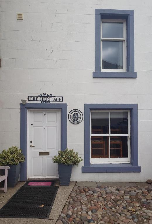 a white building with a door and a sign on it at The Heritage Guest House in Montrose