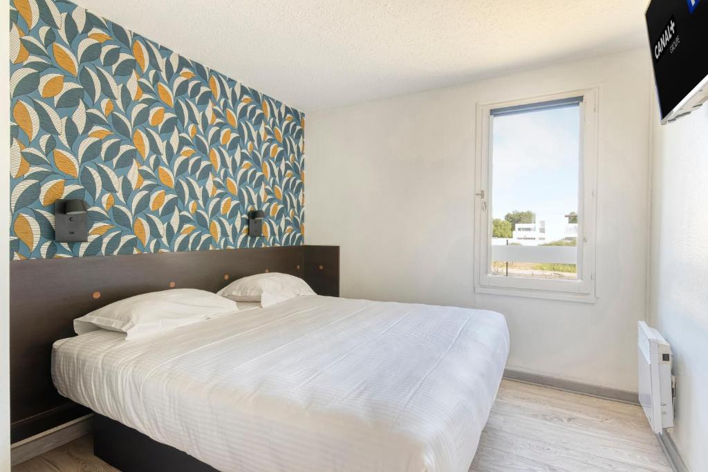 a bedroom with a large bed and a window at Fasthotel Angers Beaucouzé in Beaucouzé