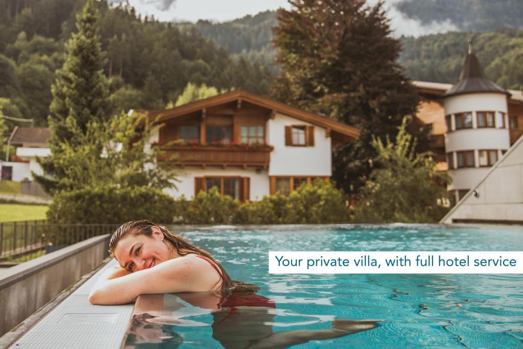 a woman is laying in a swimming pool at Villa Schwarzbrunn in Stans