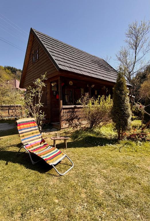 a chair sitting in the grass in front of a house at Woodenhouse Maramures in Vişeu de Sus