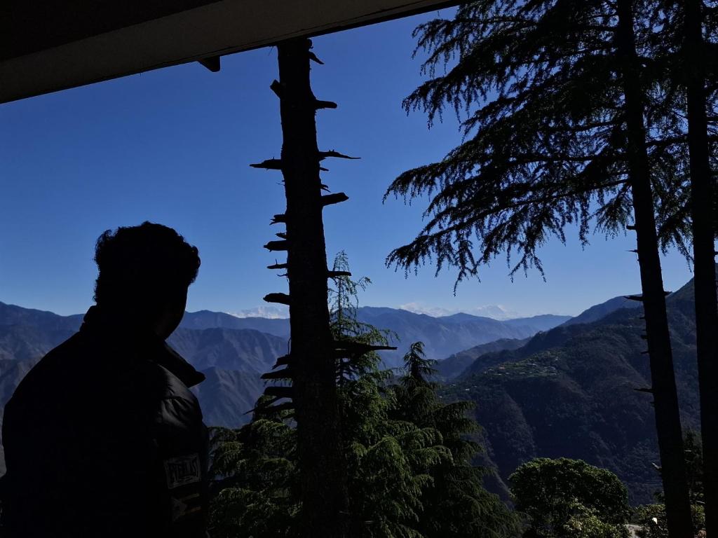 a man standing in front of a window looking at the mountains at ONHILLs in Mussoorie