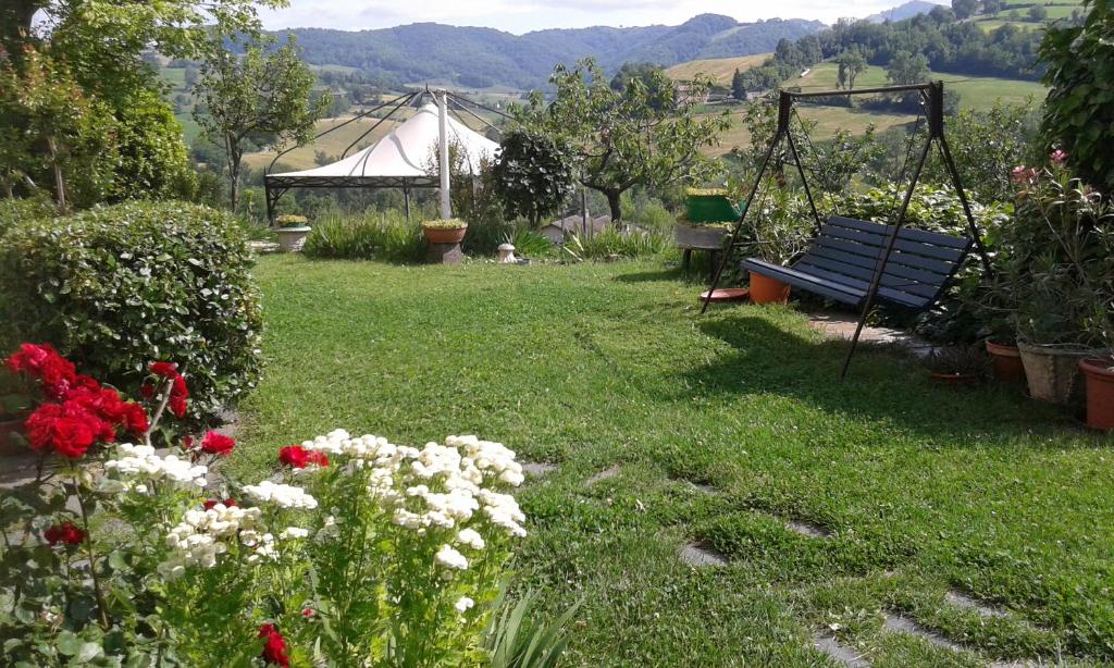 een tuin met een bank en bloemen in het gras bij Casa Bruna in Salsomaggiore Terme
