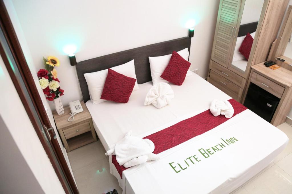 een slaapkamer met een wit bed met rode kussens bij Elite Beach Inn in Hulhumale
