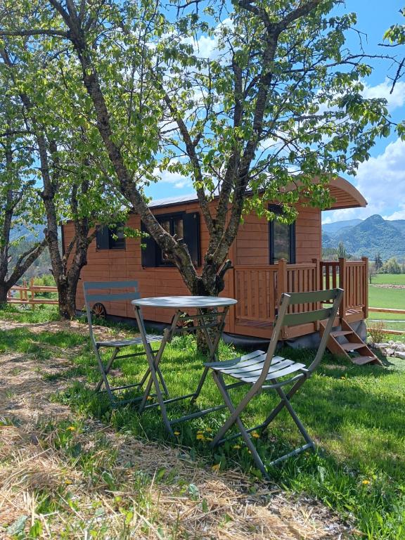 a picnic table and a bench in front of a cabin at La roulotte des foins in Montmaur
