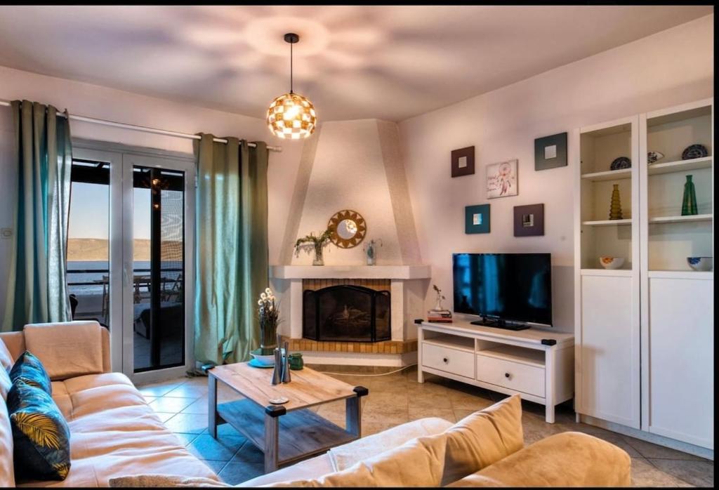 a living room with a couch and a tv at Aegean Verde Retreat in Sounio