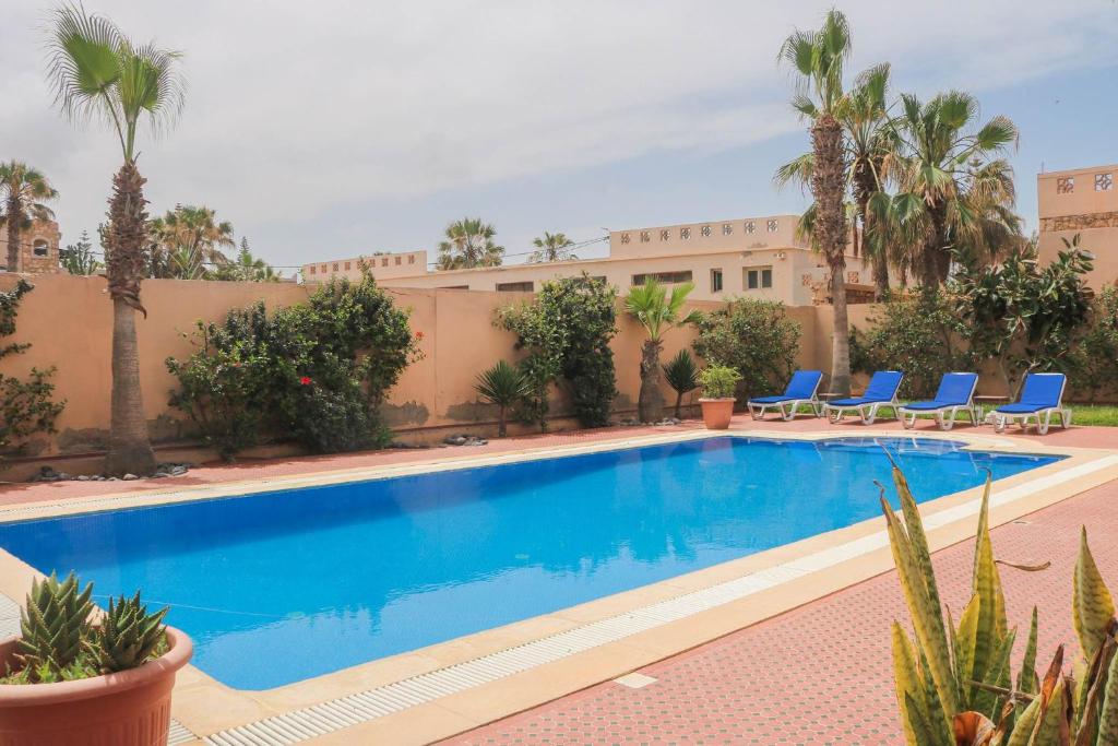 a swimming pool in a resort with blue chairs and palm trees at Spacious 3 bed 2 bath villa with Garden and Pool in Mirleft