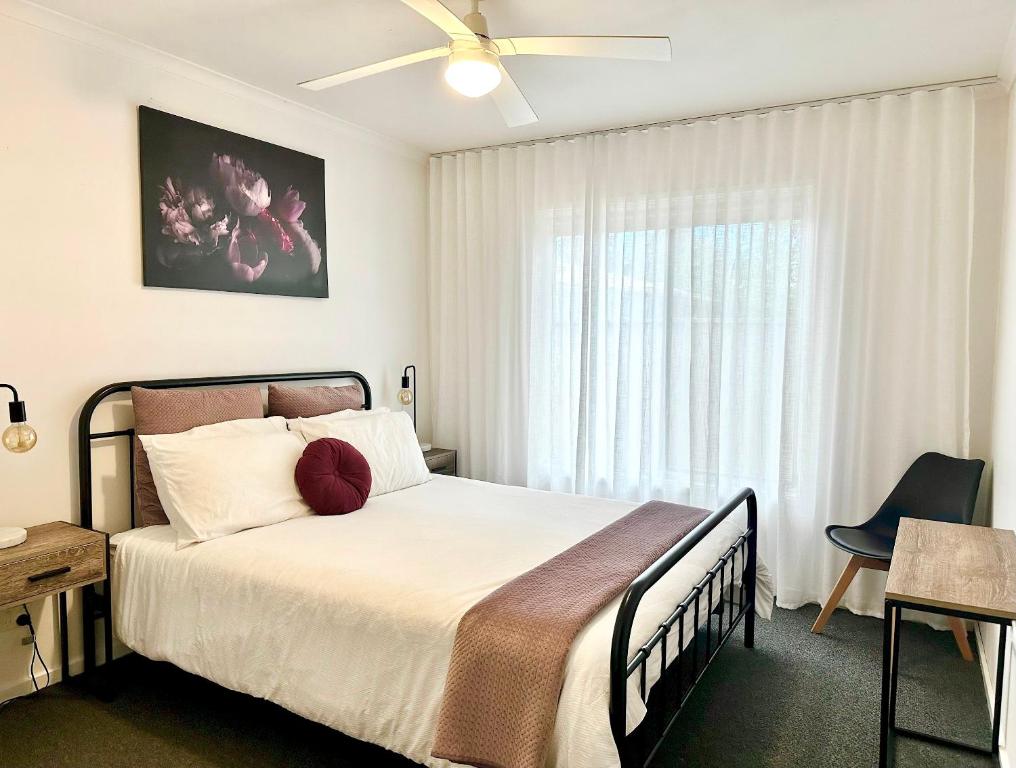 a bedroom with a bed with a ceiling fan and a window at Sunny Shackell - family and pet friendly in Echuca