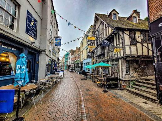 an empty city street with tables and chairs and buildings at The Salty Loft in Hastings