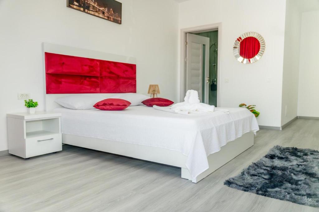 a white bedroom with a large white bed with red pillows at R & A Resident in Năvodari