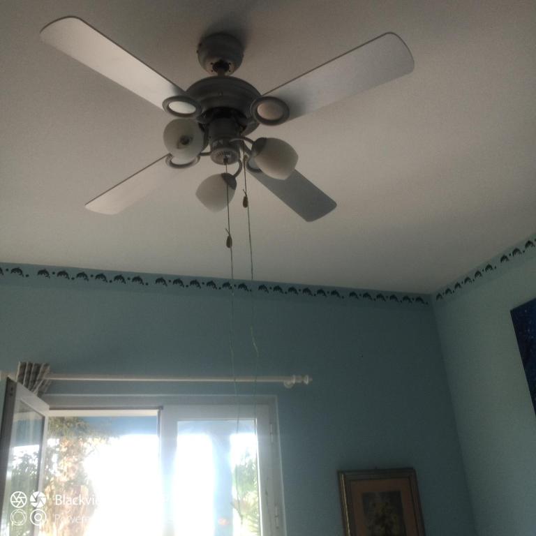 a ceiling fan in a room with a window at Ca Azul in Tarrafal
