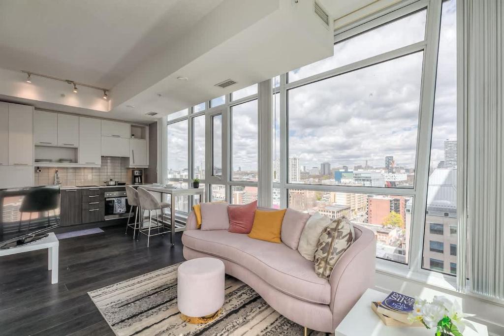 a living room with a couch and a large window at CN Tower Views - 2BR Condo - Balcony - Fast Wi-Fi in Toronto