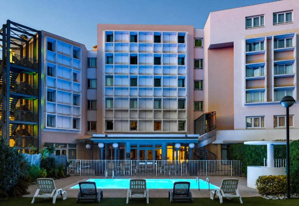 a hotel with a pool in front of buildings at B&B HOTEL Marseille Bonneveine in Marseille