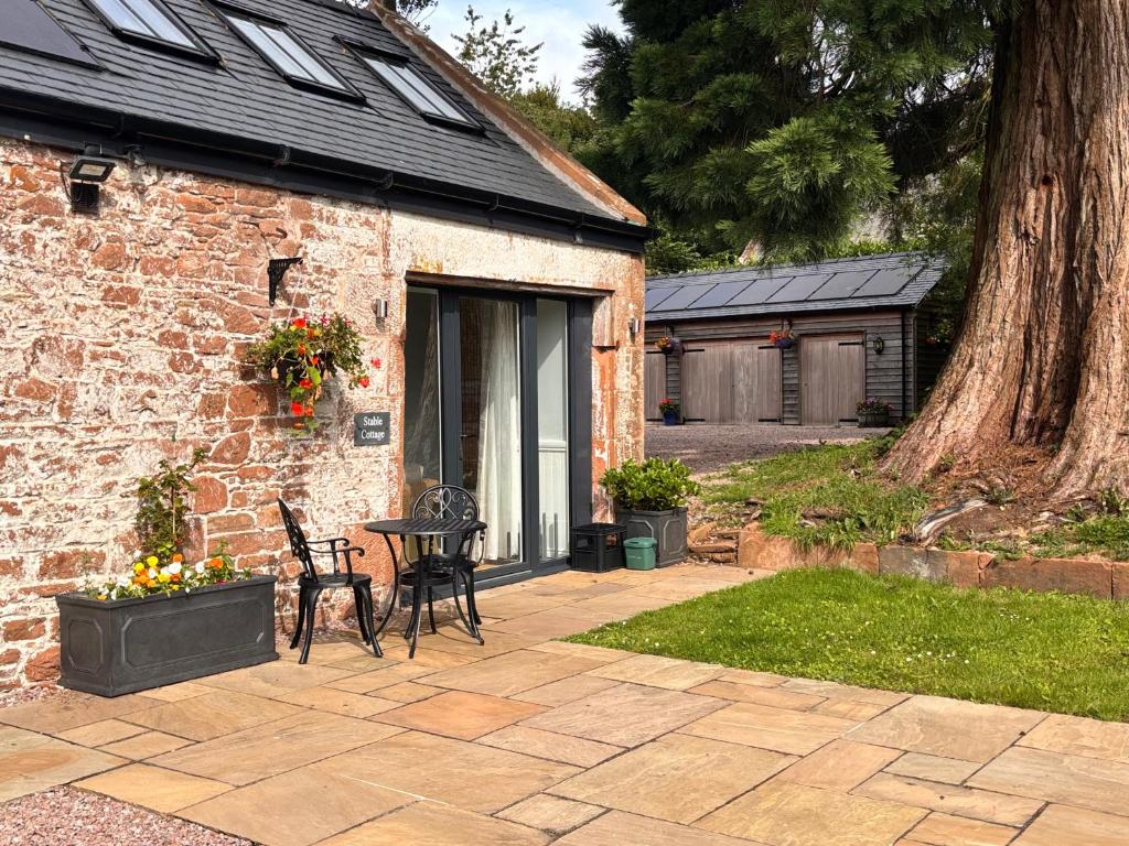 a patio in front of a brick building with a table at Stable Cottage in Lockerbie