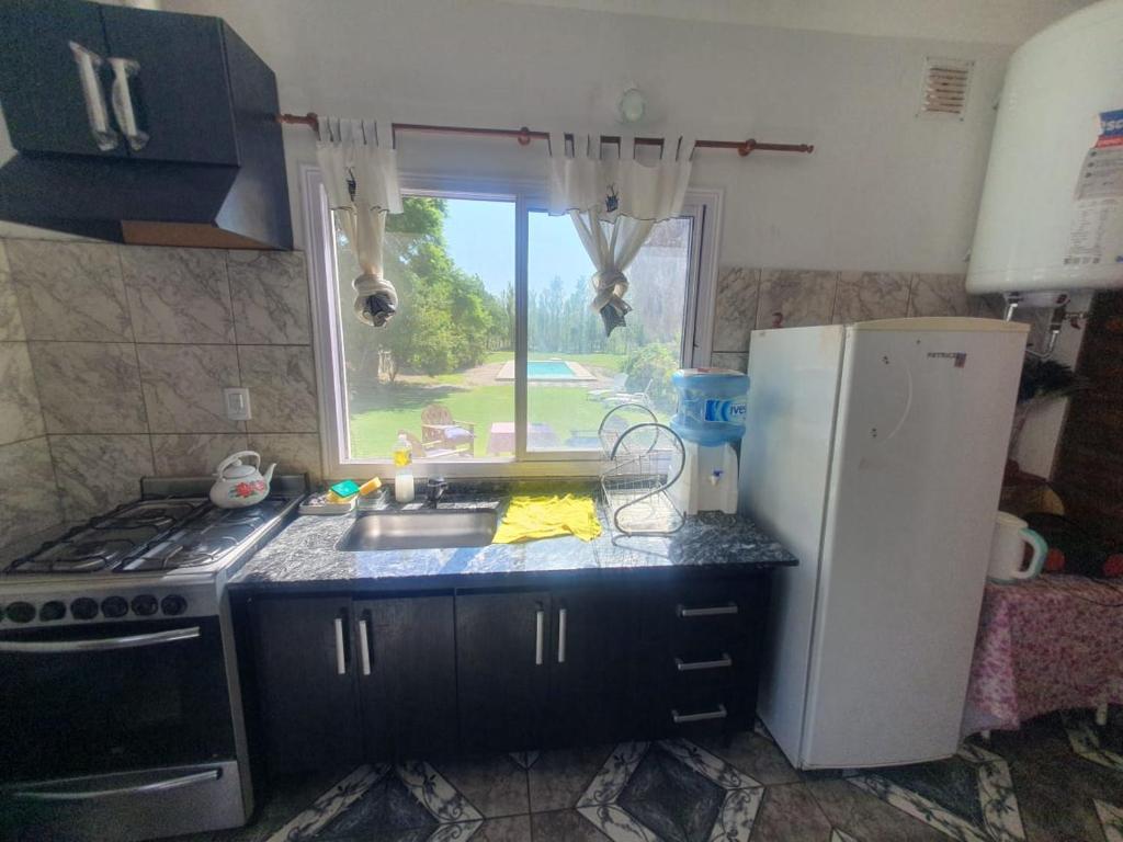 a kitchen with a sink and a refrigerator and a window at El Rincón de mis Abuelos in Albardón
