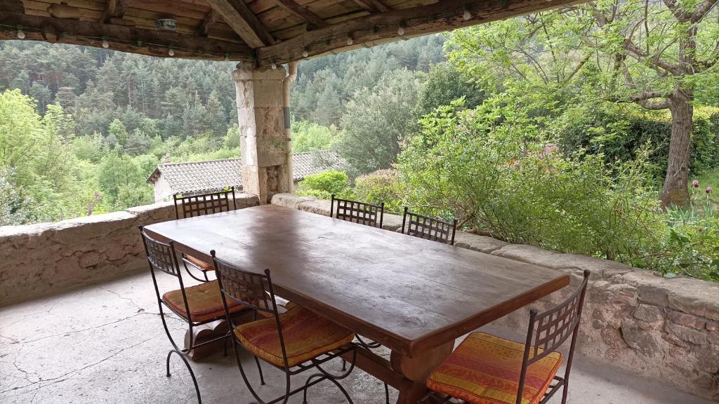 a wooden table and chairs on a porch with a view at Logis de Rocles in Rocles
