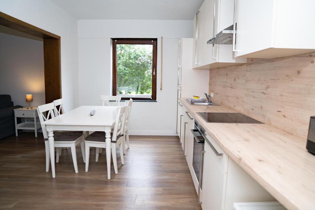 a kitchen with a white table and a table and chairs at Ferienwohnung BEA 1 in Rabenkirchen-Faulück