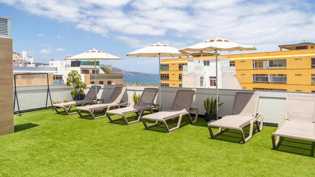 a patio with chairs and umbrellas on a roof at URBANSEA Las Palmas in Las Palmas de Gran Canaria