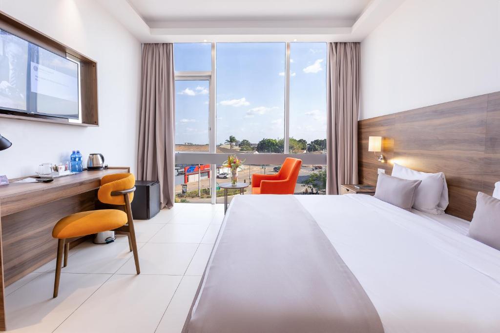 ein Hotelzimmer mit einem großen Bett und einem Schreibtisch in der Unterkunft Seen Ran Hotel Bouake in Bouaké