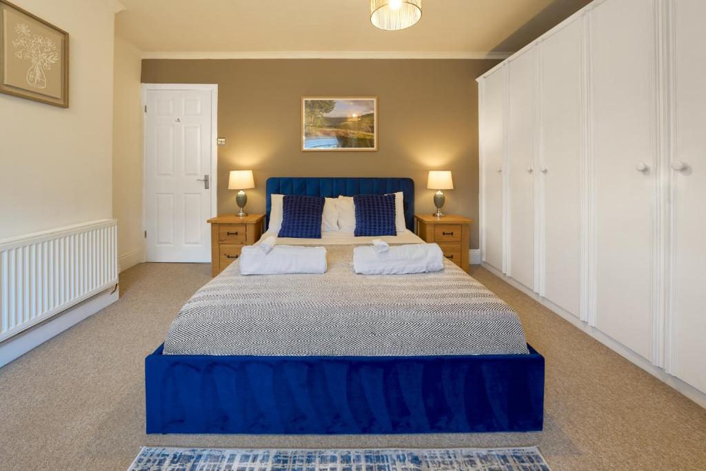 a large blue bed in a bedroom with two night stands at Cosy Peak District Cottage Walk to Town Centre in Fairfield
