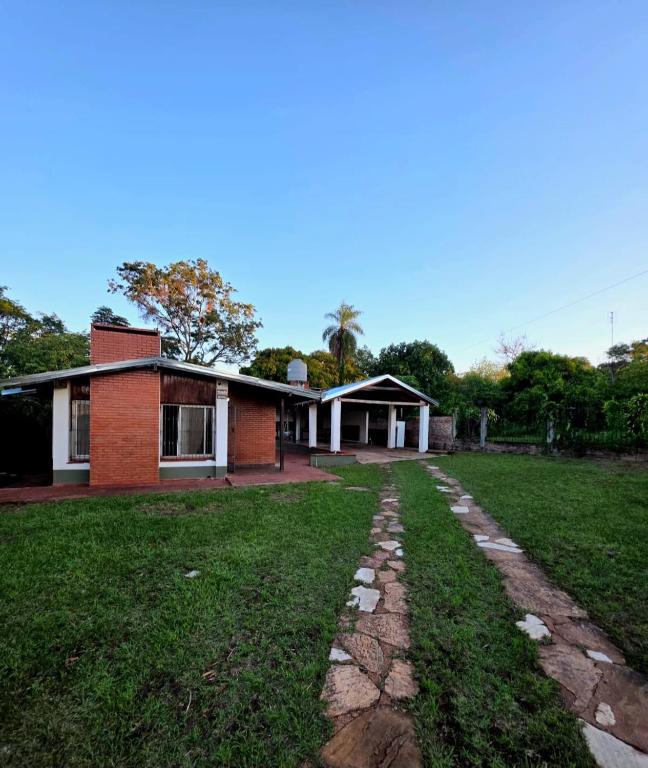 a brick house with a grass yard in front of it at El Refugio Misiones in Garupá