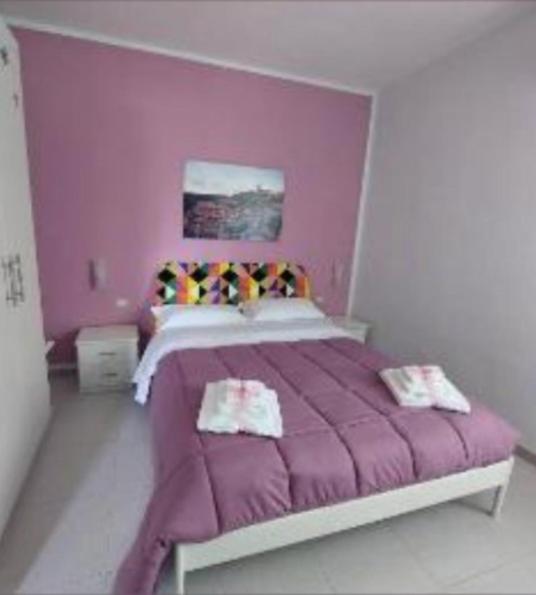 a pink bedroom with a bed with purple sheets at La Collinetta Dei Sassi in Matera