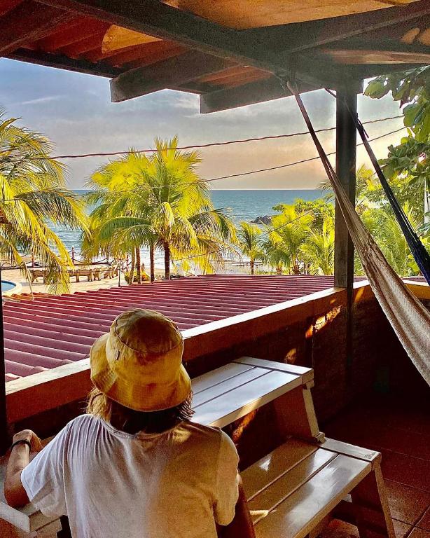 a person sitting on a bench looking at the ocean at Bananoz Surfhouse in Transito