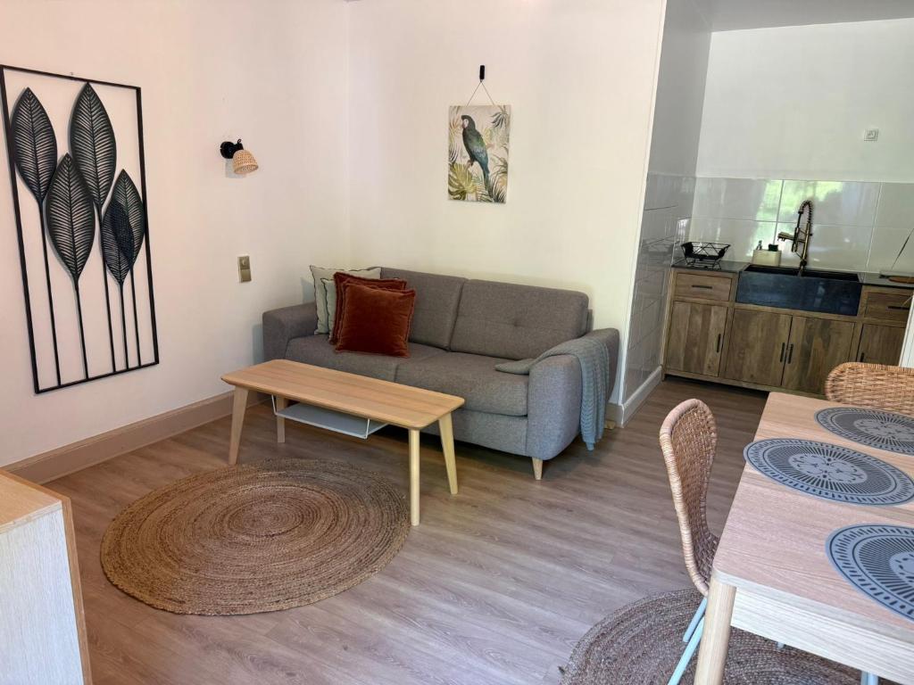 a living room with a couch and a table at logement avec accès piscine in Chaumont-sur-Tharonne