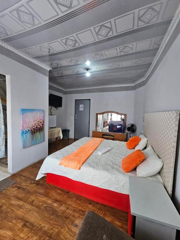 a bedroom with a large bed with orange pillows at TURFLOOP guest house in Mankweng