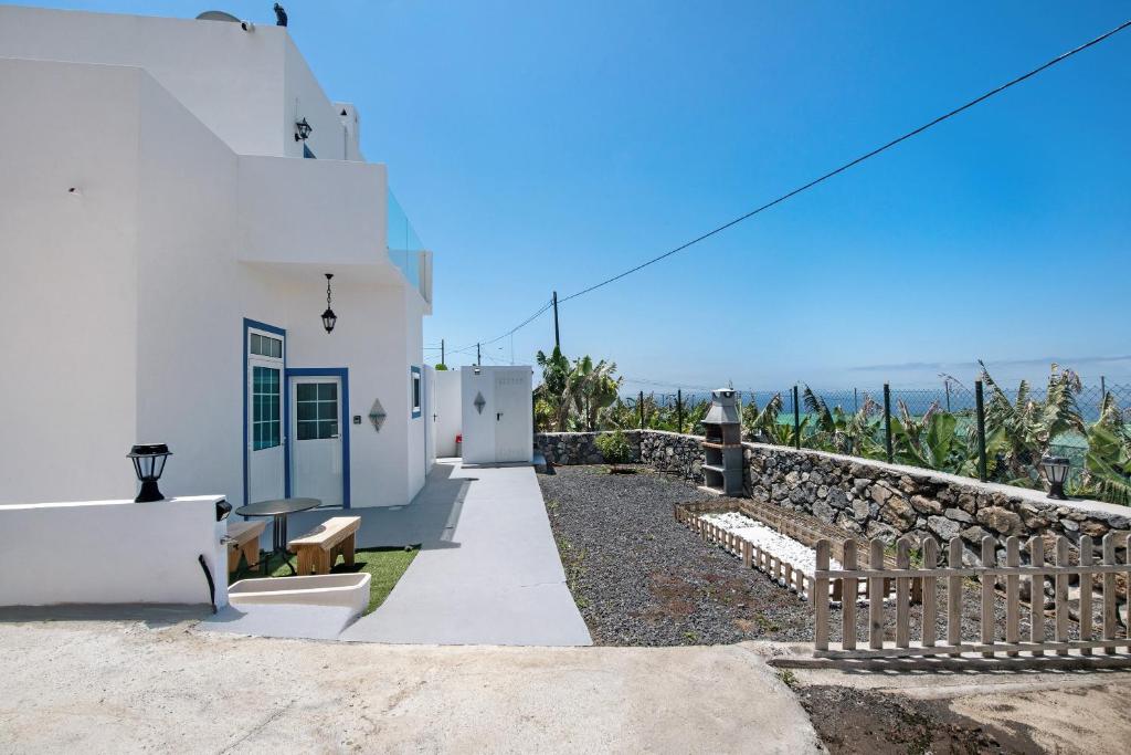 a white house with a stone wall and the ocean at vv Rincón Solaris in Tijarafe