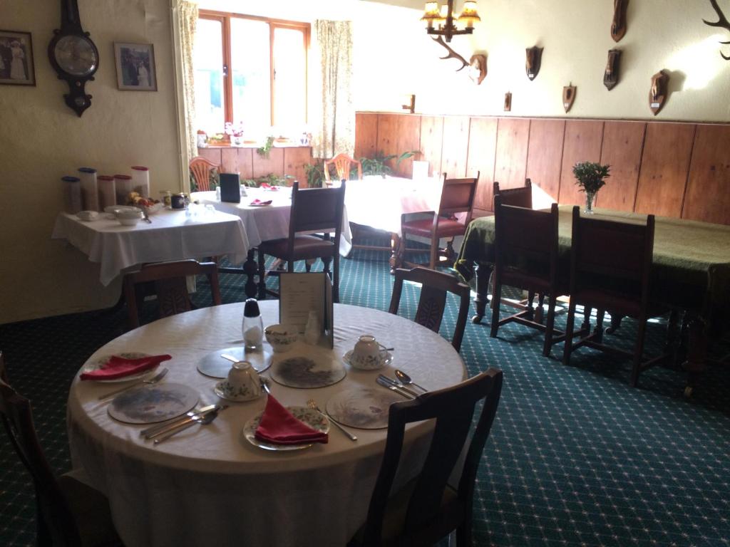 a dining room with tables and chairs and a table with dishes at Coombe Farm in Lynton