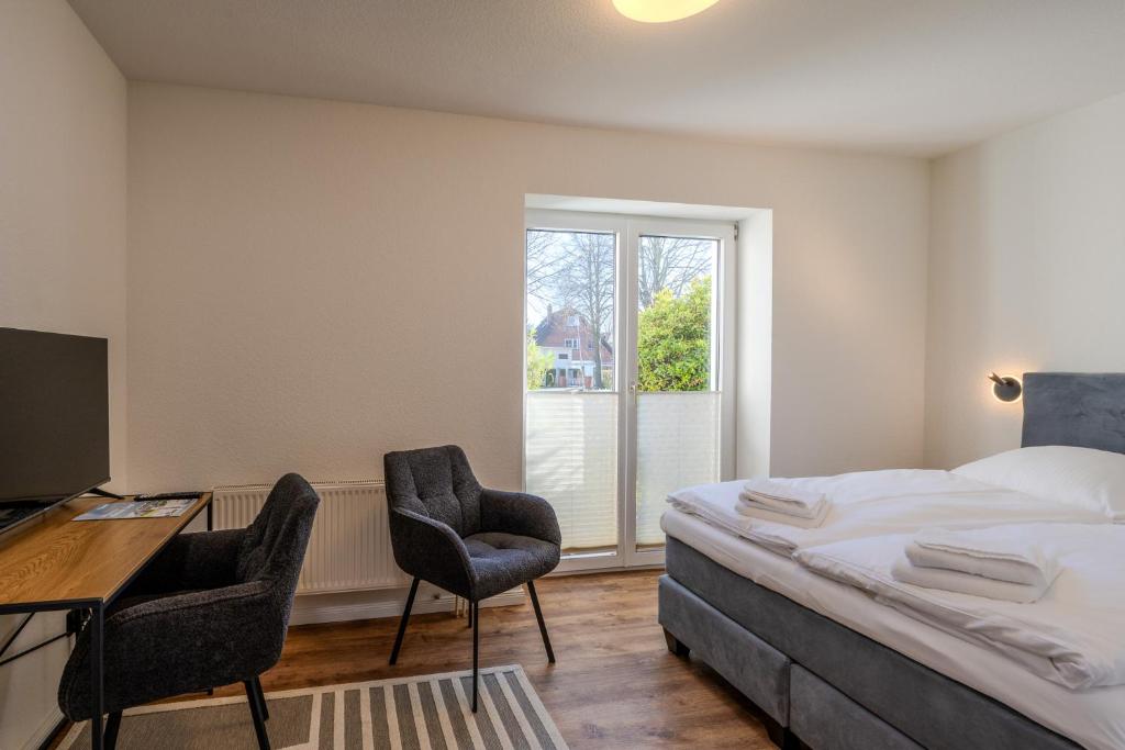 a bedroom with a bed and two chairs and a desk at Johouse Zingst Johouse Zimmer 01 in Zingst