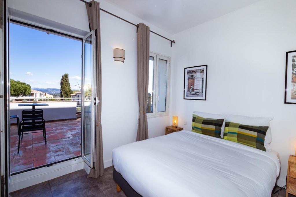a bedroom with a bed and a balcony with a table at Hôtel la Rotonde in La Croix-Valmer