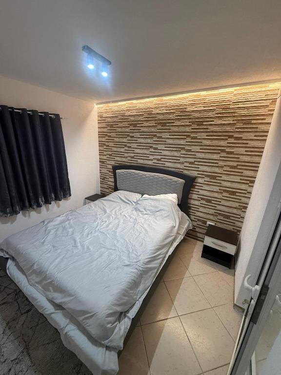 a bed in a room with a brick wall at Baywatch Apartmans in Brca