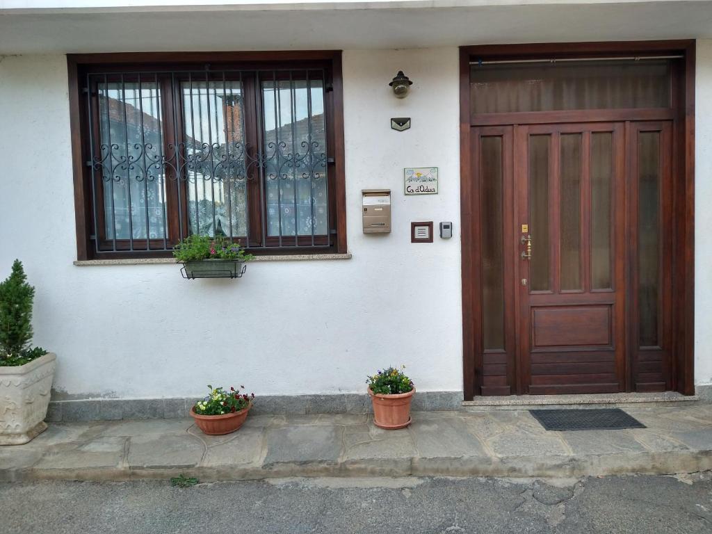 Ein Haus mit zwei Topfpflanzen vor der Tür in der Unterkunft CA d'ADUA in Pray