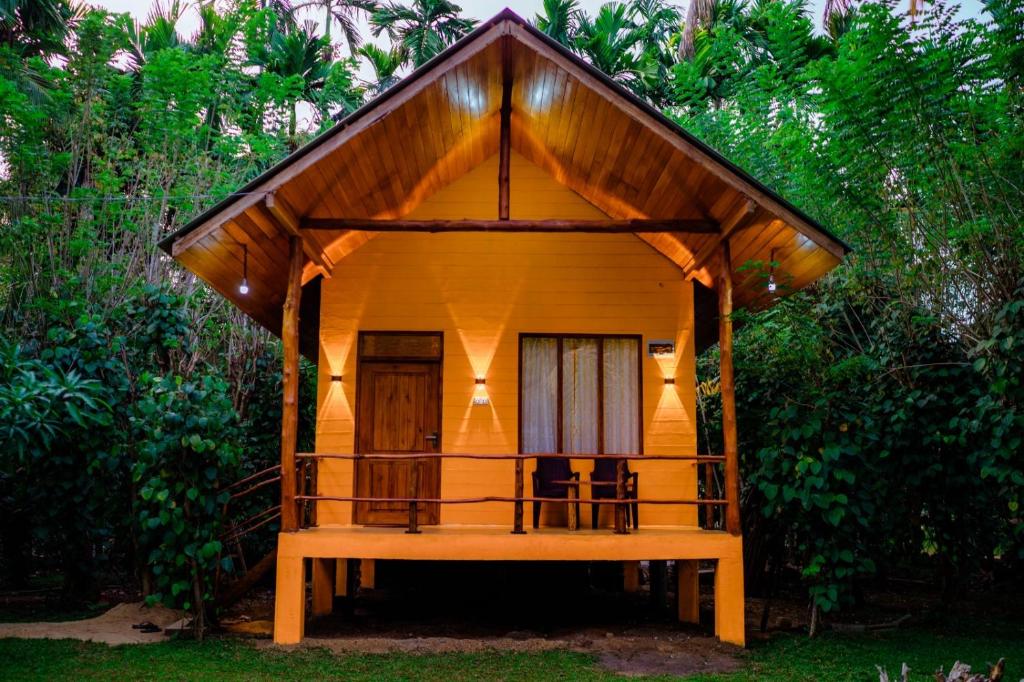 a small wooden house with a thatched roof at Walawa Wild Place in Udawalawe