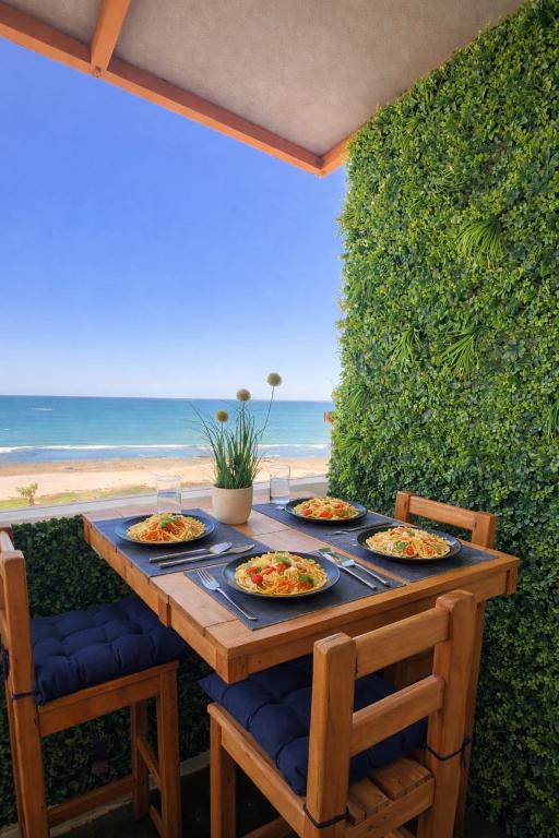 a table with plates of food on it with the beach at Ocean view sunset apartment in the heart of Rabat in Rabat