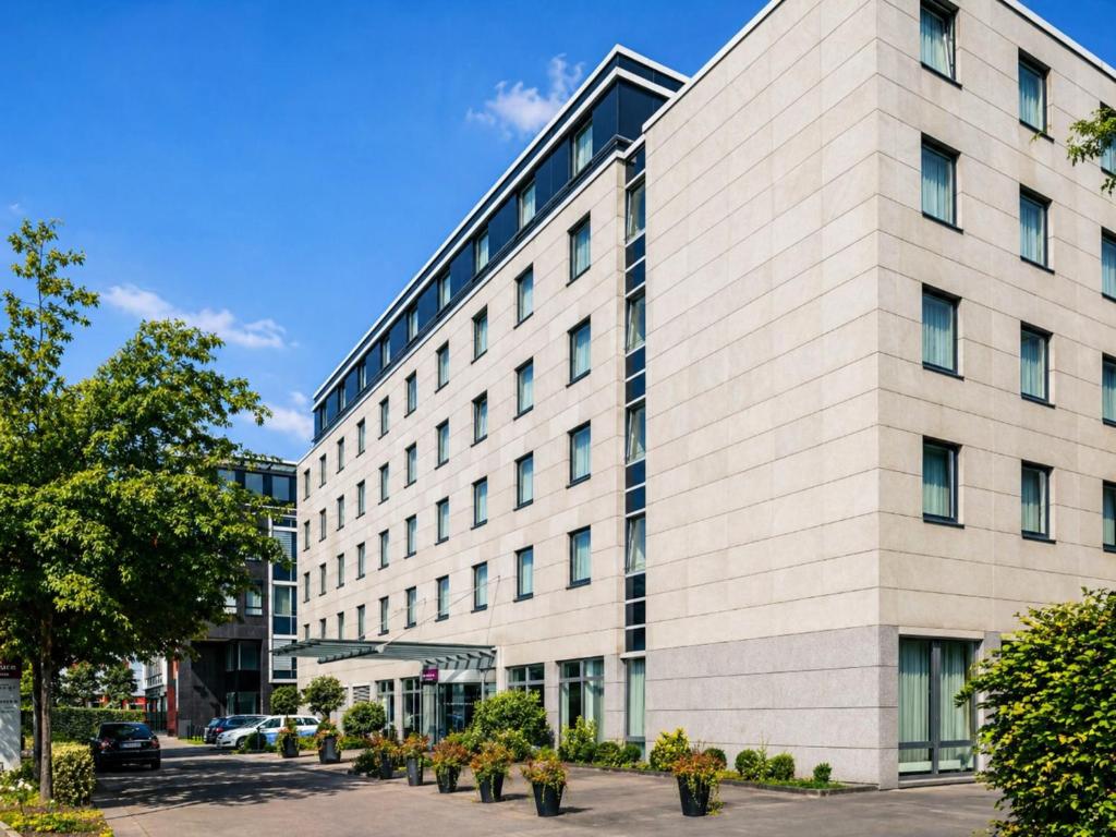 a large white building with windows on a street at Sunday Hotel Düsseldorf City Nord in Düsseldorf