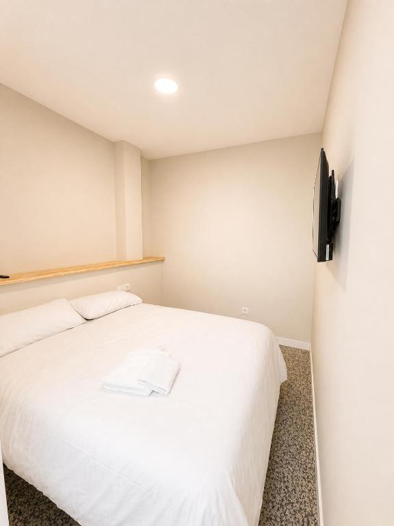 a bedroom with a white bed and a television at Hostal Majadahonda in Majadahonda