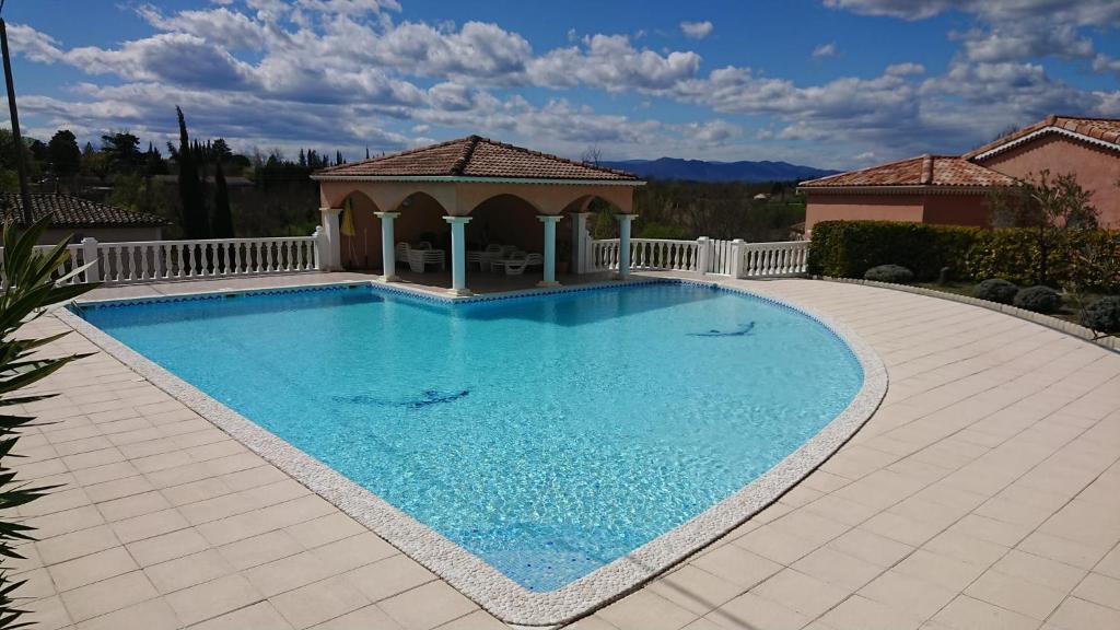 a large blue swimming pool in a yard at Gîte Barbera "Les Oliviers" in Grospierres