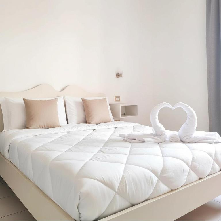 a white bed with two white swans on it at ELEGANCE GIBA Rooms in Giba