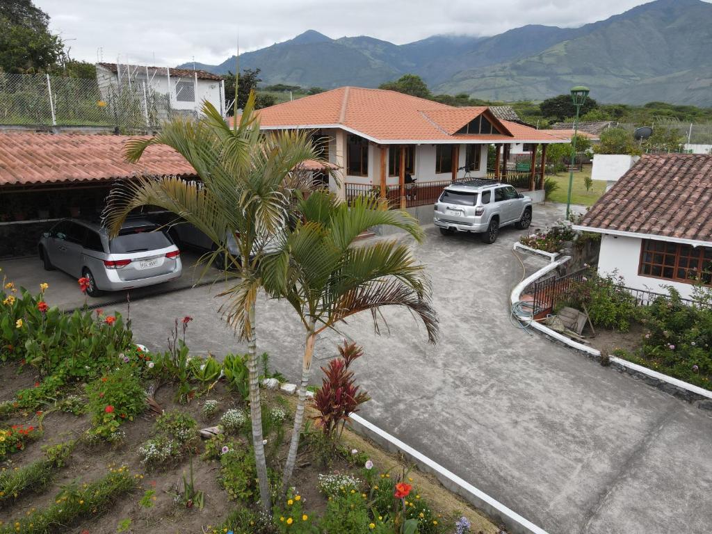 a house with two cars parked in a parking lot at Quinta 4 esquinas cerca de Chachimbiro in Hacienda San Clemente