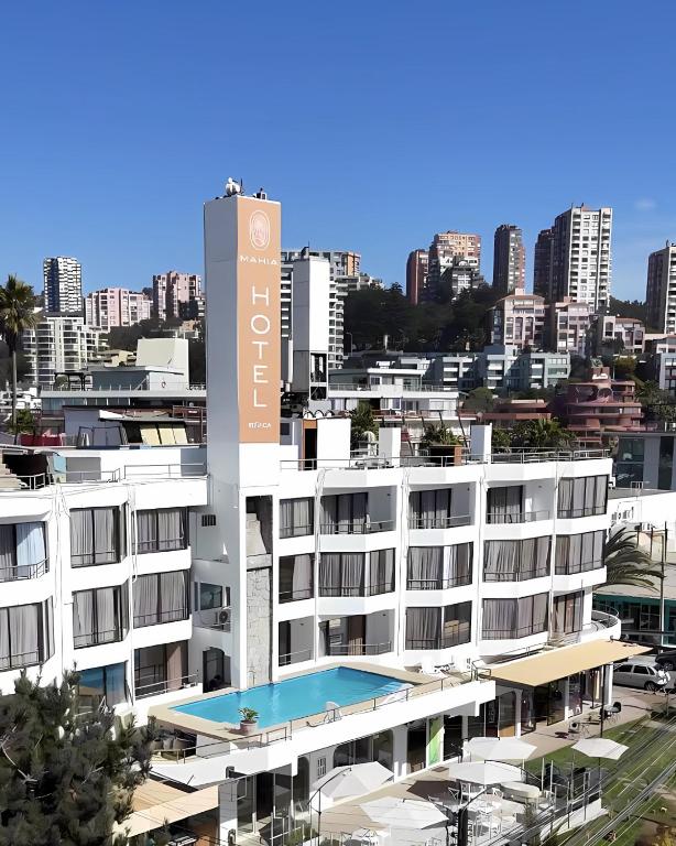 a large white building with a swimming pool in front of a city at Mahia hotel Reñaca in Viña del Mar