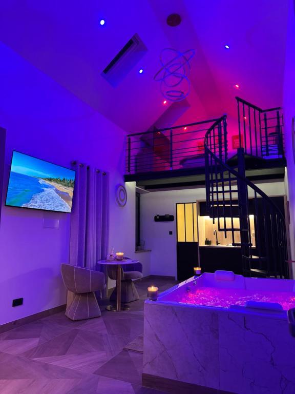 a purple room with a couch and a tv and a table at Spa Signature in Dijon
