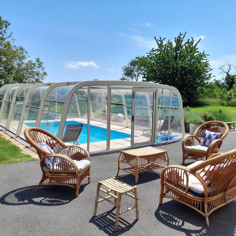 a group of chairs and tables in front of a glass house at Chambre d'hôtes Chez Sarah in Saint-Bon