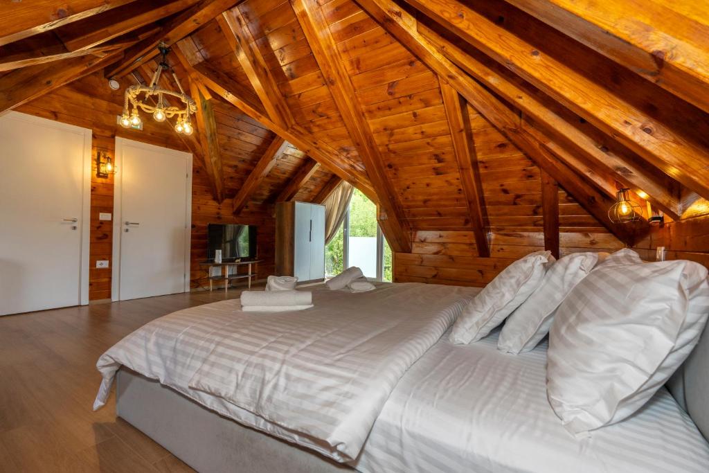 a large bed in a room with wooden ceilings at KayakHotel in Ndërlisaj