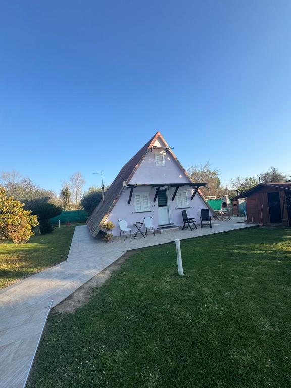 a thatch roofed house with a patio and grass at La casina di Ginevra in Marina di Massa